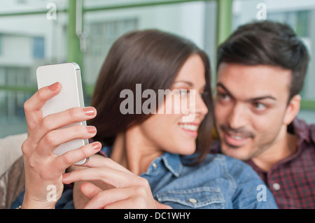 Junges Paar zu Hause mit Blick auf Handy Stockfoto