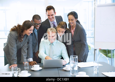 Lächelnde Geschäftsleute Austausch Laptop im Konferenzraum Stockfoto