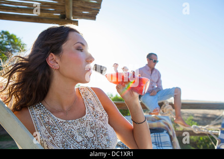 Junge Frau trinkt aus der Flasche in der Sonne Stockfoto