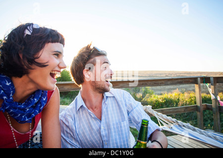 Junges Paar auf sonnigen Balkon sitzen und Lächeln Stockfoto