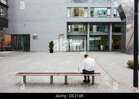 Rückansicht der Mann liest beim Sitzen auf der Bank im öffentlichen Platz / Raum - Dublin Irland Stockfoto