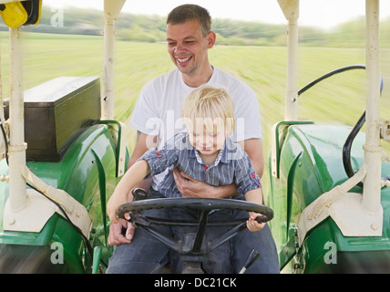 Reifer Mann, sitzend mit Sohn im Traktor, Lächeln Stockfoto