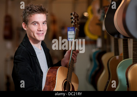 Junger Mann, Blick auf Gitarren im Music store Stockfoto