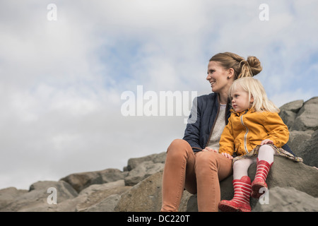 Mutter und Kleinkind sitzen auf der Hafenmauer Stockfoto