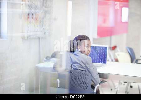 Junge Frau mit Computer im Büro Stockfoto