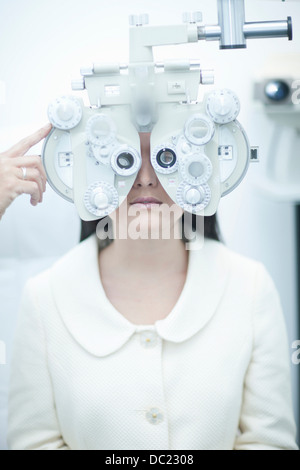 Junge Frau, die Augen beim Optiker testen Stockfoto