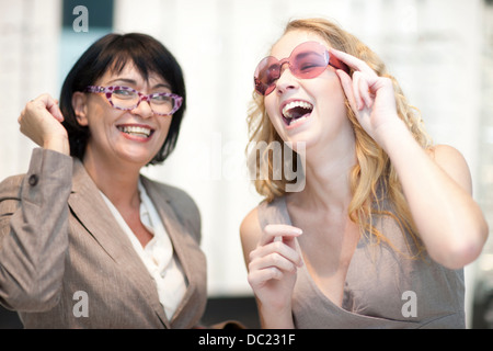 Zwei Frauen lachen während Brillen anprobieren Stockfoto