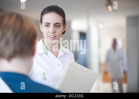 Krankenschwester mit Patienten und Notizen an der Rezeption Stockfoto