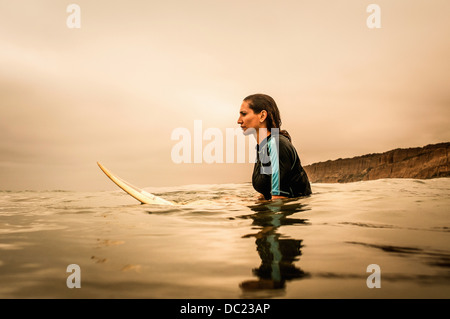 Junge Frau im Meer mit Surfbrett, Profil Stockfoto