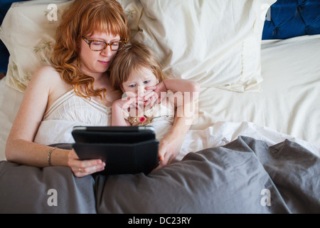 Mutter und Tochter im Bett liegend, Blick auf digital-Tablette Stockfoto