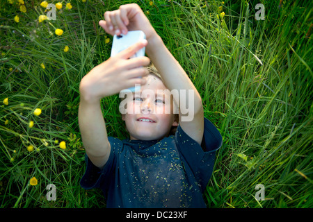 Junge liegend auf dem Rasen Selbstporträt Foto mit smartphone Stockfoto