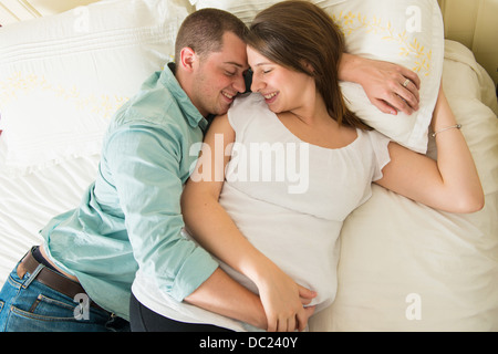 Schwangere Frau und Partner auf Bett liegend Stockfoto