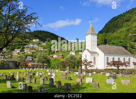 Weiße Holz stave Kirche und Friedhof im Dorf an der Küste auf Samnanger. Øystese Kvam, Hardanger, Hordaland, Norwegen Stockfoto
