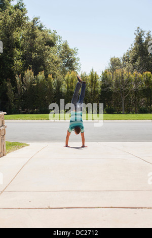 Junger Mann macht Handstand auf Auffahrt Stockfoto