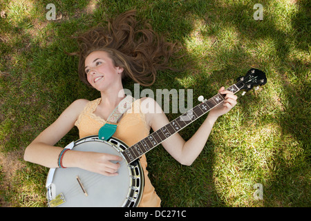 Teenager-Mädchen spielen Banjo auf dem Rasen, Draufsicht Stockfoto