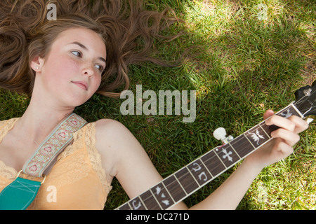 Teenager-Mädchen spielen Banjo auf dem Rasen, Draufsicht Stockfoto