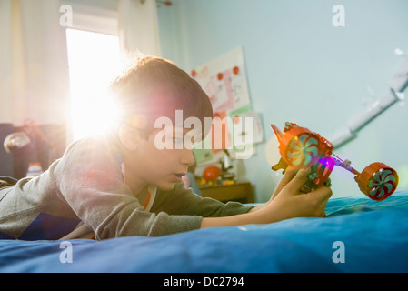 Junge auf Bett liegend mit Spielzeug Stockfoto