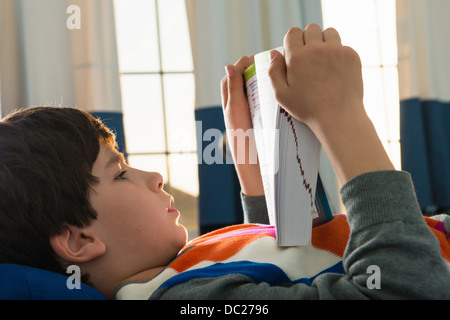 Junge auf Bett Buch Stockfoto