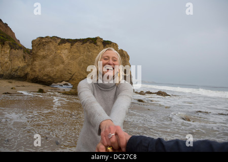 Älteres Paar halten die Hände am Strand Stockfoto