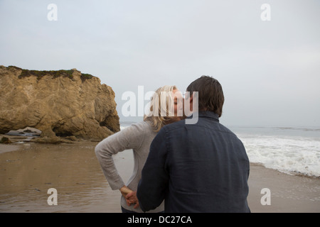 Älteres Paar küssen am Strand Stockfoto