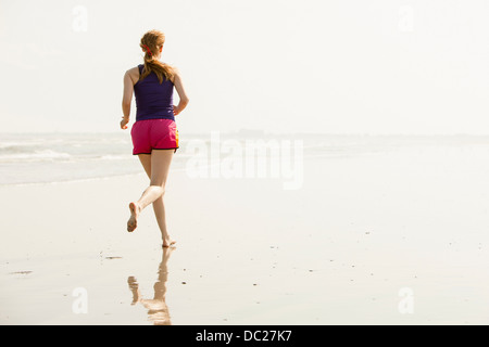 Reife Frau, Joggen am Strand Stockfoto