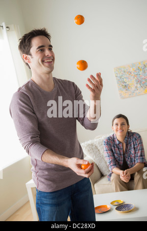 Mann jonglieren Orangen, Frau beobachten Stockfoto