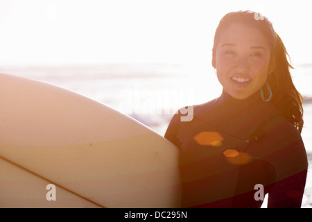 Junge Frau trägt Anzug mit Surfbrett Stockfoto