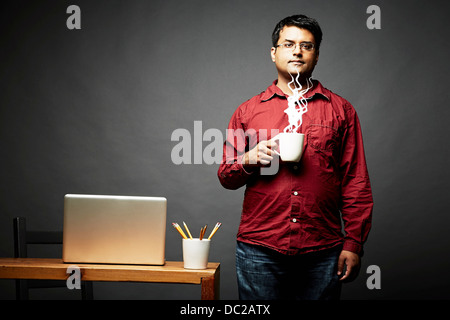 Mann hält Tasse dampfenden Heißgetränk Stockfoto