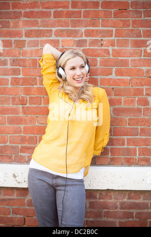 Frau trägt Kopfhörer gegen brickwall Stockfoto