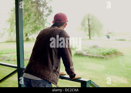 Mann auf Veranda Blick auf Garten Stockfoto