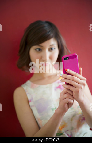 Frau gegen rote Wand mit Handy Stockfoto