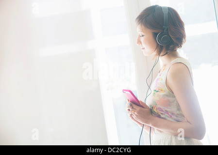 Frau anhören von Musik auf dem Handy mit Kopfhörer Stockfoto