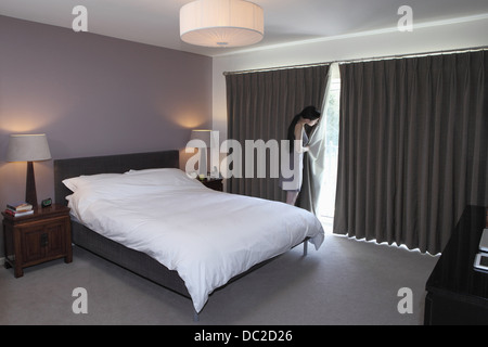 Frau hinter Bettzimmer Vorhang gucken Stockfoto