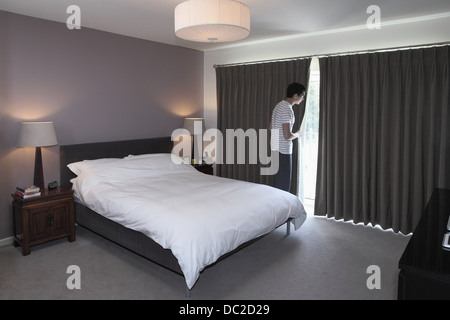 Mann hinter Vorhang Schlafzimmer gucken Stockfoto