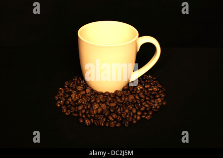 Kaffee-Haferl umgeben von frisch gerösteten Kaffeebohnen Stockfoto