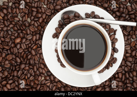 Warmes Frühstück Kaffee Tasse und Untertasse Kaffeebohnen auf rustikalen Hintergrund umgeben Stockfoto