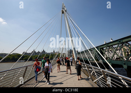 Fußgänger überqueren die Golden Jubilee Brücke über den Fluss Themse London England UK Stockfoto