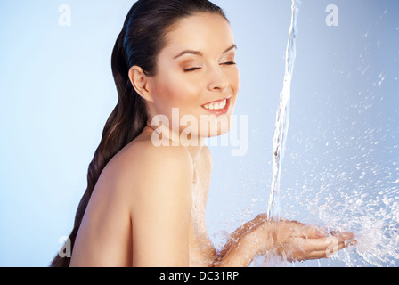 Porträt der jungen Sinnlichkeit schöne Frau unter dem Strahl des Wasser - blauen Hintergrund Stockfoto