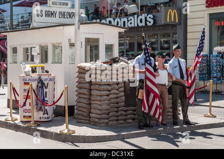 US Army Checkpoint Charlie – Frau mit Schirmmütze und Schauspieler im amerikanischen Soldaten uniform posieren - Berlin Germany Stockfoto