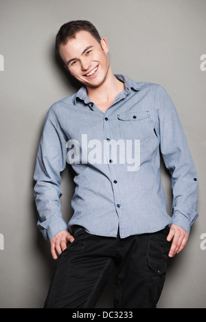 Gut aussehend lächelnder Mann lässig an die Wand gelehnt Stockfoto