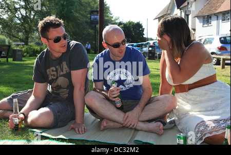 Freunde sitzen auf dem Rasen, Bier zu trinken. Stockfoto
