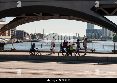 Menschen mit Fahrrädern auf der Oberbaumbrücke Blick auf die Spree und die Skulptur Molecule Man - Berlin Stockfoto