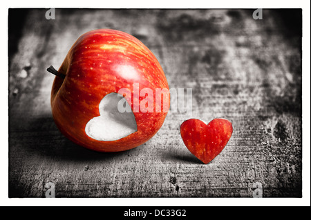 Ein roter Apfel mit einer Herzform-Ausschnitt. Einerseits ist in der Farbe und der andere Teil ist schwarz & weiß. Darstellung der Liebe. Stockfoto