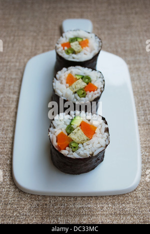Vegetarische Maki Sushi-Rollen mit Reis, Karotten, Zucchini, grüne Bohnen, Tofu und Nori Algen in weiße Schale auf natürlichen Hintergrund Stockfoto