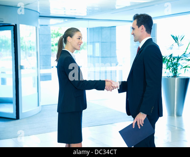 Lächelnde Geschäftsmann und Geschäftsfrau Handshaking in lobby Stockfoto