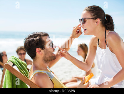 Paar, die Anwendung von Sonnenschutzmitteln, gegenseitig die Nase am Strand Stockfoto