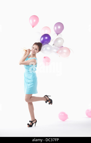 eine Dame in Minikleid posiert mit Luftballons Stockfoto