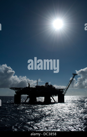 Silhouette einer Bohrinsel im Offshore-Bereich, harte Gegenlicht, blauen Himmel, Refelection auf der Wasseroberfläche. Stockfoto