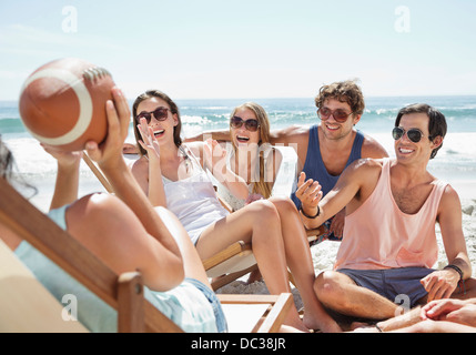 Glückliche Freunde mit Fußball hängen am Strand Stockfoto