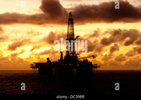 Silhouette von einer Offshore-Bohrinsel fern am Horizont zu Sonnenaufgang/Sonnenuntergang Zeit. Stockfoto